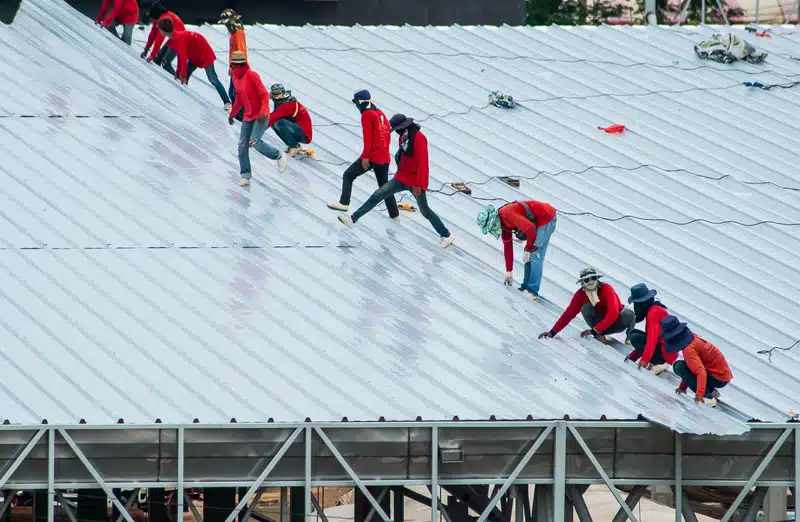 team of roof repairman installing roof recover over an existing roof 