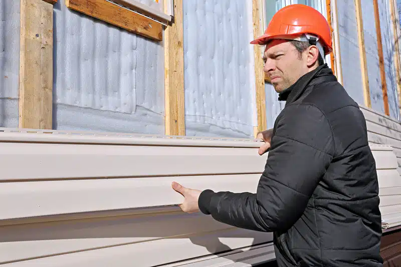 man installing siding of a house