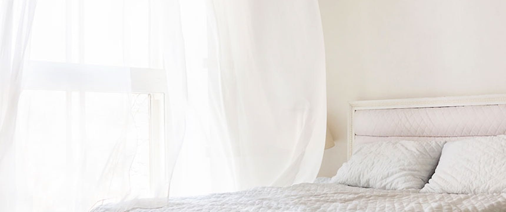 White bedroom with window open and air blowing through the window. Fixing drafty rooms