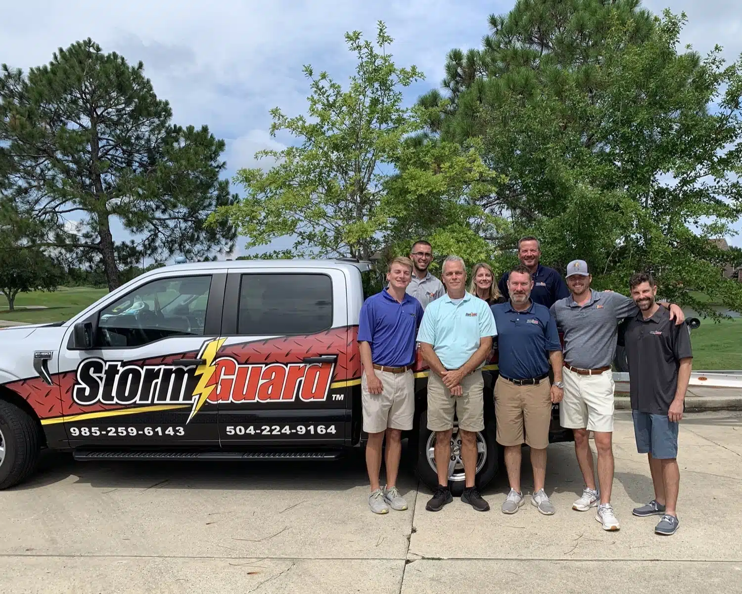 8 people staning beside a truck, Storm Guard employees