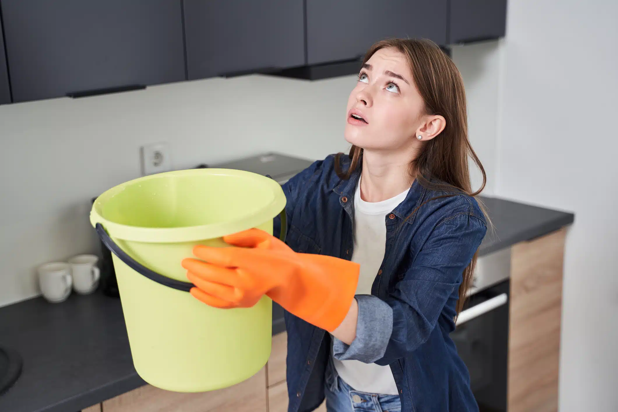 A lady holding a container catching the water leak from the roof