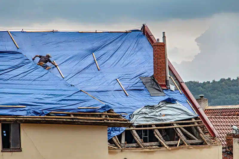 damaged roof with emergency roof tarp | roofing insurance claims in New Orleans