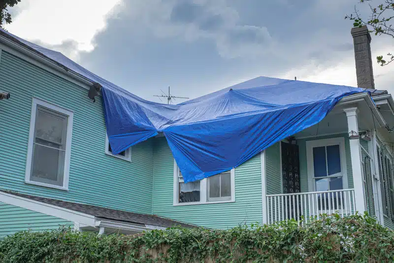 damaged roof with emergency roof tarp