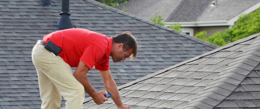 Roofing professional inspecting asphalt shingles on a residential roof