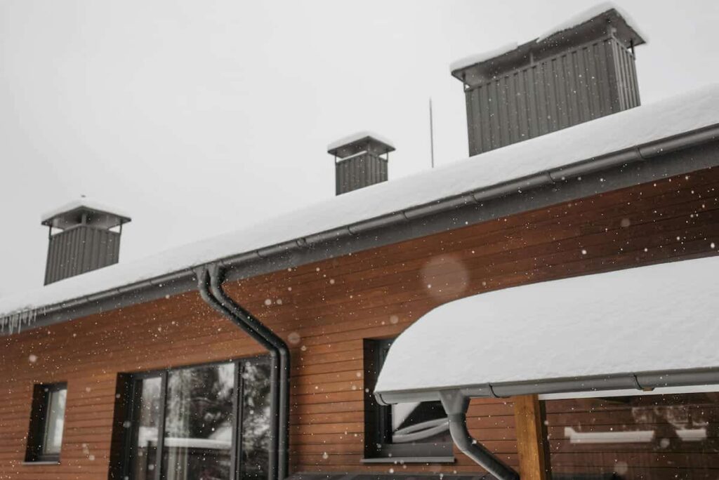 Snow-covered roof and gutter on a home in winter, where ice dams and heavy snow loads can form