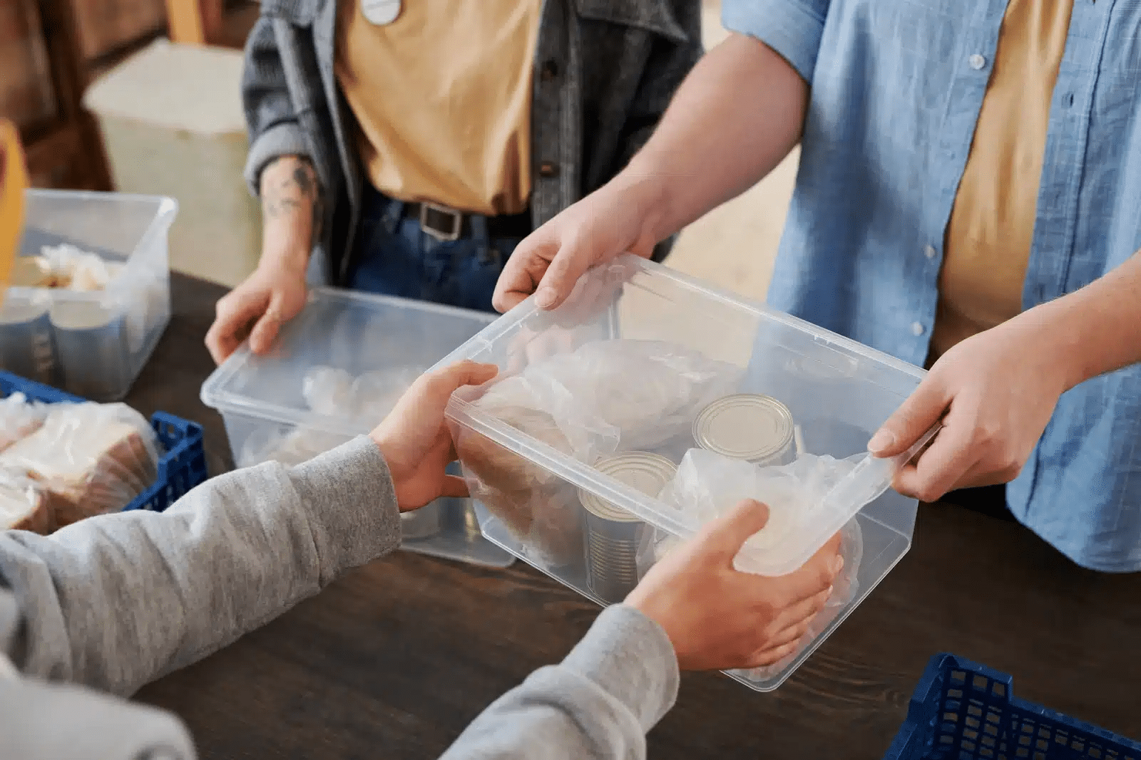 Volunteers distributing food supplies in plastic containers at a community outreach event