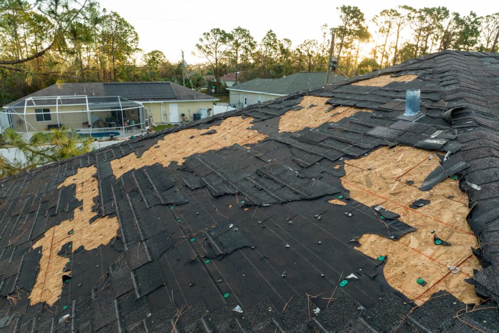 Storm-damaged residential roof with missing shingles exposing roof decking