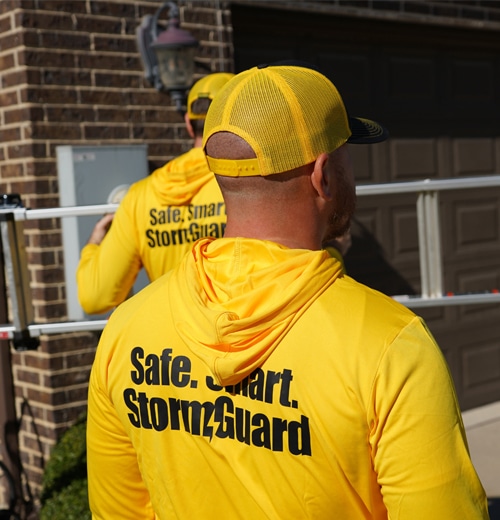 Storm Guard team members wearing yellow safety jackets on a residential job site