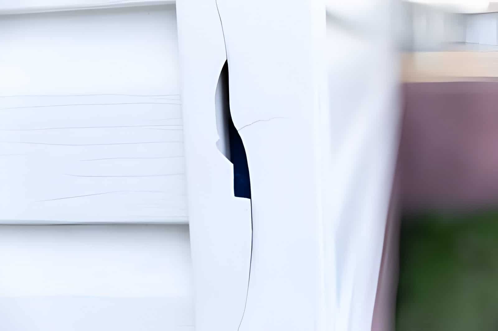 Close-up of cracked vinyl siding exposing exterior damage