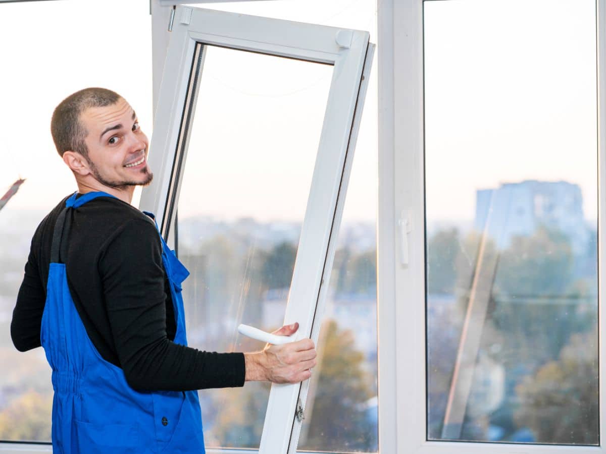 Professional installer fitting a new white vinyl window frame in a home